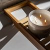 candle with 3 wicks sitting on a shelf over a bathtub
