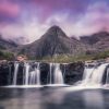 a sunset pink sky above a small waterfall and mountain at the fairy pools on the isle of skye