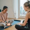 two women sit on yoga mats holding candles thinking of the health impacts of candles
