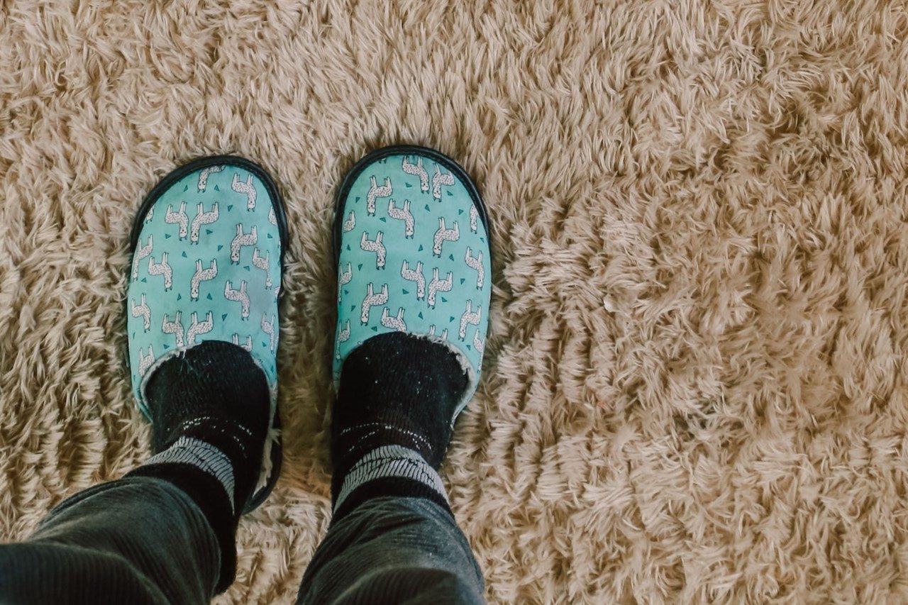 someone wearing slippers standing on a carpet after removing candle wax