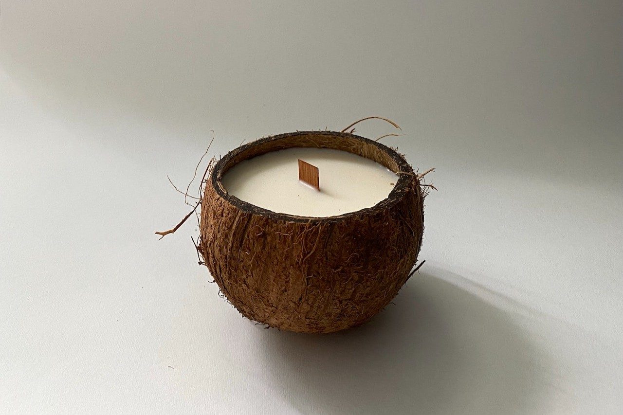 Half a coconut filled with coconut wax and a wooden wick