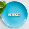 a blue plate with scrabble letters spelling out vegan, with a green leaf entering the image from the right. Used for a blog about vegan candle