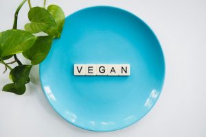 a blue plate with scrabble letters spelling out vegan, with a green leaf entering the image from the right. Used for a blog about vegan candle