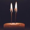 A candle with two wicks alight in the dark. If you want to know what double wicking is, this is a double wicked candle. Although the wicks are too long in this image