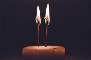 A candle with two wicks alight in the dark. If you want to know what double wicking is, this is a double wicked candle. Although the wicks are too long in this image