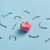 A small pink candle sits in the middle of the image with parts of used candle wicks laying surrounding the candle. Important to know what is best to choosing your wick