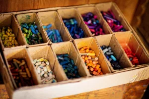 A box of used crayons with individual compartments for different colours. Can be used for adding colour to plain candles to turn into crayons, it is one idea about what to do with leftover candle wax.