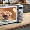 An open microwave oven in a modern kitchen with a bowl of colourful wax chunks inside. Can you microwave soy wax? We find out here using a bowl that is clear glass, sitting on the microwave's rotating plate. The kitchen has modern countertops and some appliances visible in the background. The scene is well-lit, emphasising the vibrant wax colours and the microwave.