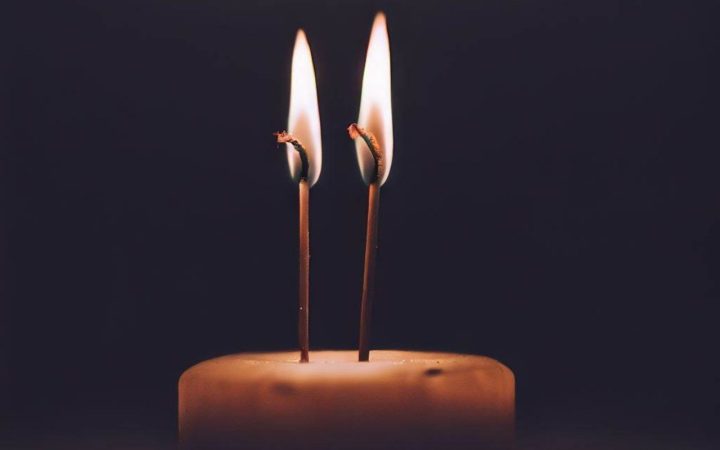 A candle with two wicks alight in the dark. If you want to know what double wicking is, this is a double wicked candle. Although the wicks are too long in this image