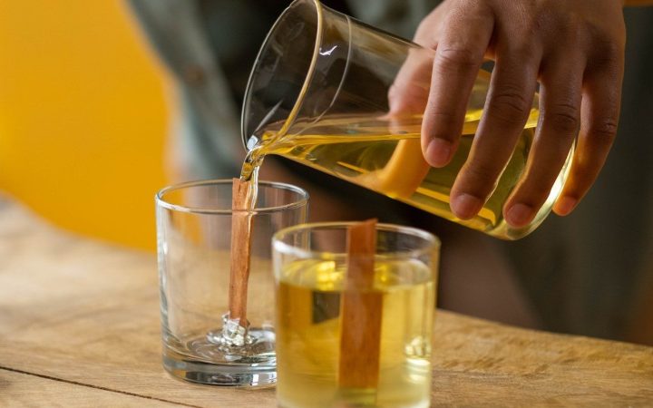 A woman is making hand-poured candles on a wood table with wooden wicks