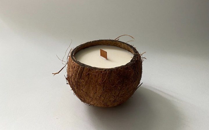 Half a coconut filled with coconut wax and a wooden wick