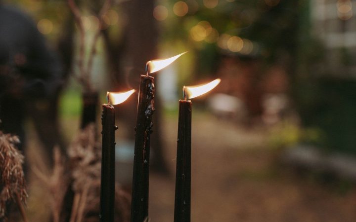 Three candles stand outdoors with the flame flickering in the wind showing why candles flicker