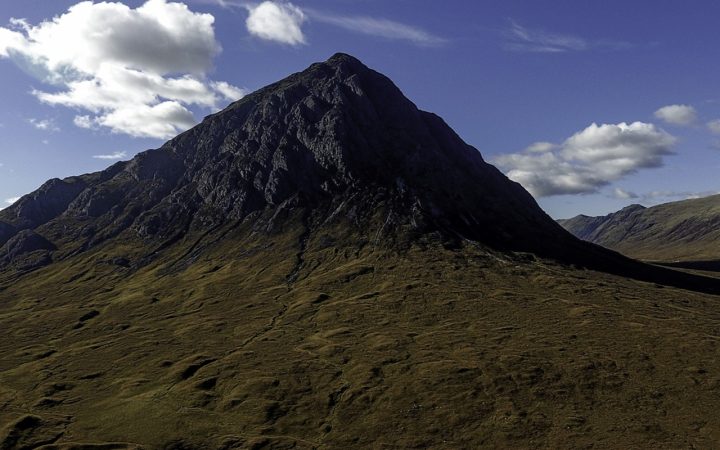 The mountain Buachaille Etive Mòr in Glen Coe appears under a blue sky