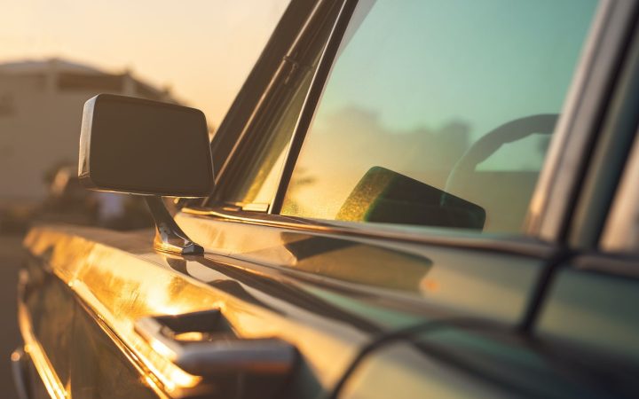The side of a car door and window with the sun against it, wondering if a candle will melt in a hot car